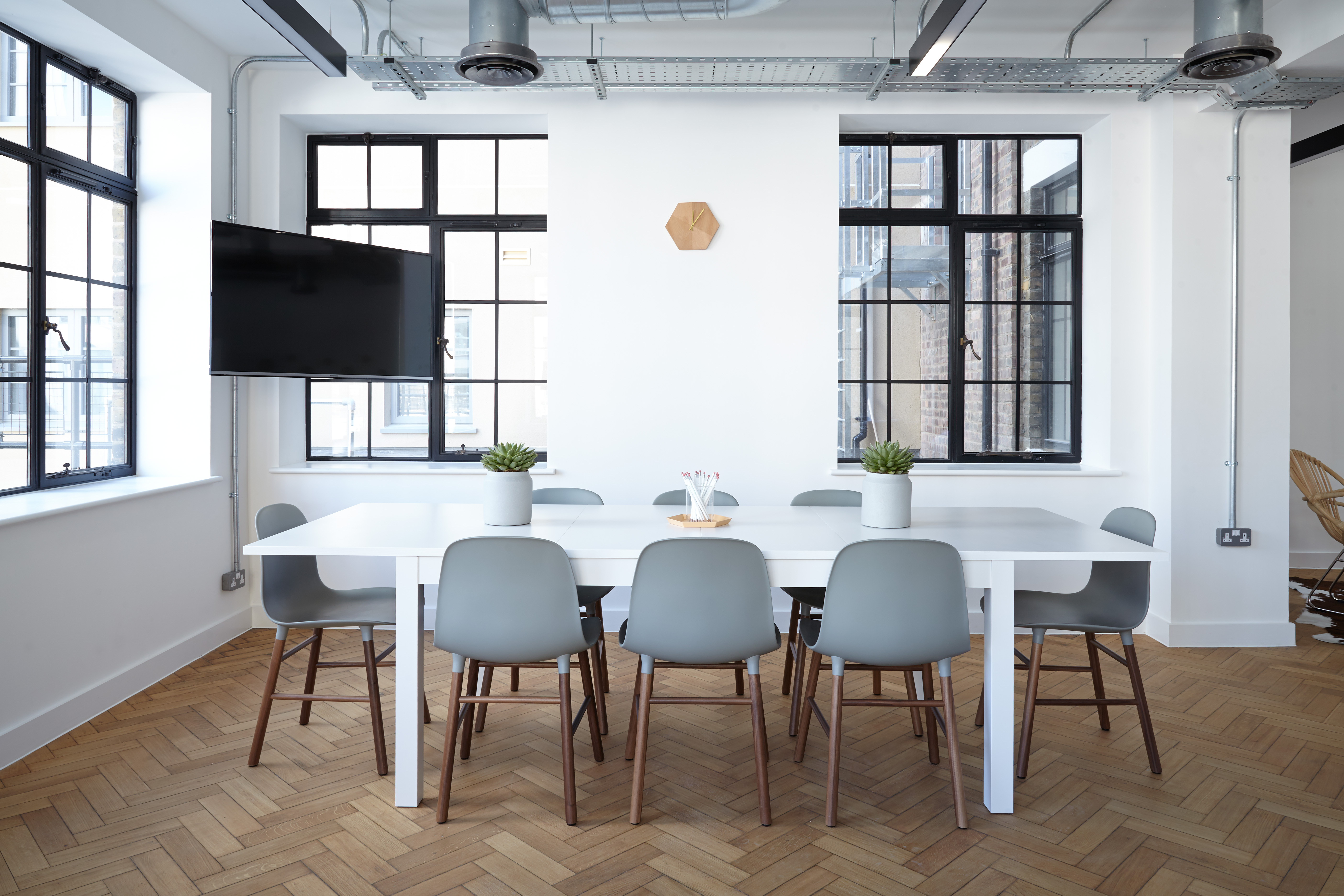 Bright modern conference room with herringbone wood floors and natural light from large windows